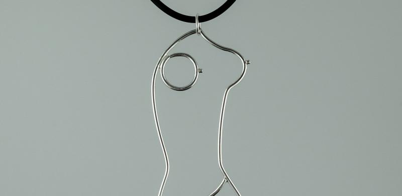 Photograph of a silver wire pendant shaped like a female torso on a black cord.