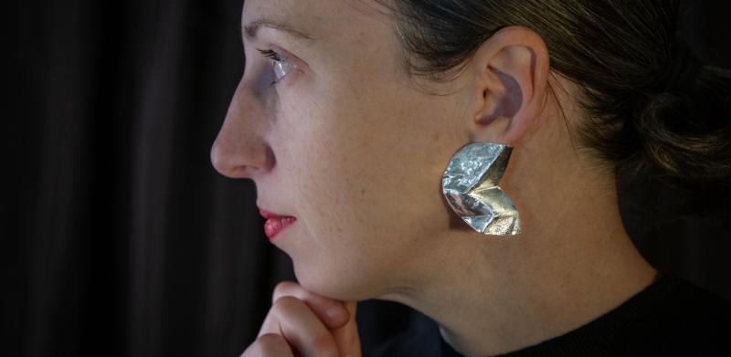 Photograph of a woman in profile wearing a metallic earring.