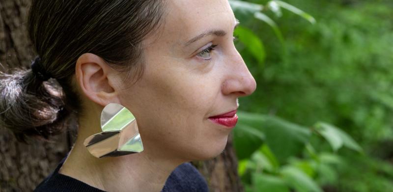 Photograph of a woman with large earrings in a forest.