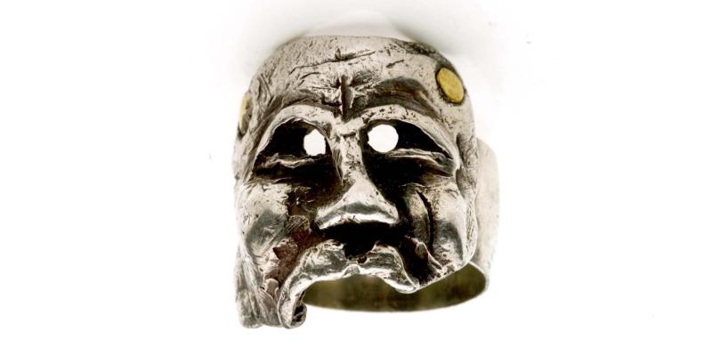 Photograph of a silver ring shaped like a tragic face.