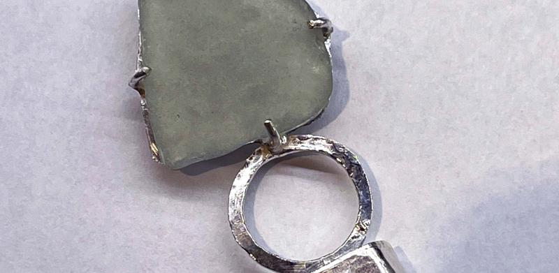 Photograph of a sea glass pendant on a black cord.