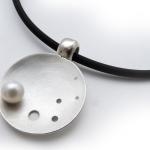 pearl on domed circular silver piece with black neck cord 
