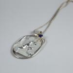 Photograph of a textured silver pendant with a small purple stone on a silver chain.