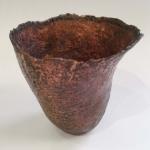 Photograph of a small, textured copper-colored bowl with an organic, uneven rim.