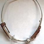 A silver necklace with dark wood accents and a small spherical pendant.
