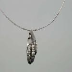 Photograph of a silver pendant shaped like a textured, stylized claw on a thin chain.
