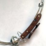Photograph of a silver wire neckpiece with a dark wooden clasp detail and a metallic sphere.