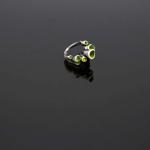 A modern silver ring with small, vibrant green accents on a dark reflective surface.