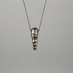 Photograph of a tapered silver pendant hanging from a thin dark string.