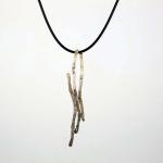 Photograph of a long, metallic, abstract branch pendant on a thin black cord.