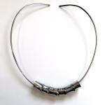 A silver open-ended neck collar featuring five cylindrical metal beads.