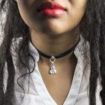 Photograph of a person wearing a black ribbon choker with a silver pendant.