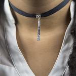 A person wearing a black ribbon choker necklace with a silver vertical pendant.