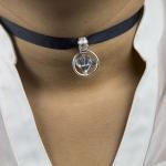Close-up of a black fabric choker with a circular silver pendant.