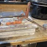 Photograph of a metalworking tool clamped to a stack of tiles on a workbench.