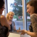 Photo of three women smiling while looking at a display case.