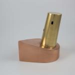 A small sculpture made of a copper base and a tilted brass cylinder.