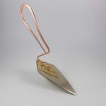 A modern cake server with a copper loop handle and a triangular blade.