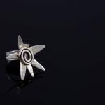 Photograph of a silver star-shaped ring on a black surface.