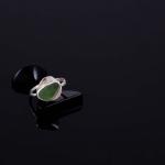 Photograph of a silver ring with a green sea glass stone on a black surface.