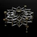 A complex, radial mechanical device of interlocking brass and silver bars against a black background.