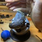 Photograph of a person shading an intricate bracelet on a jeweler's block.