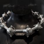 Photograph of a silver spiked necklace on a black mannequin.