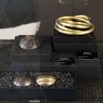 Photograph of metal jewelry pieces displayed in black boxes with labels.