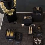 Display of unique jewelry pieces, including a large gold necklace and various earrings in boxes.
