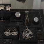 Display case with handmade silver jewelry pieces including earrings and necklaces.