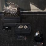 Photograph of jewelry on display with dark boxes and labels.