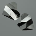 Two silver, geometric, heart-shaped earrings on a grey background.