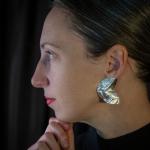 Photograph of a woman in profile wearing a metallic earring.
