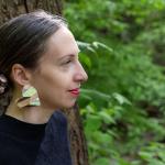 Photograph of a woman with large earrings in a forest.
