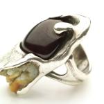 Photograph of a silver ring set with an garnet gemstone and a tooth.