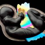 Photograph of a dark, stylized sculpture of a curled fetus holding an iridescent sheet.