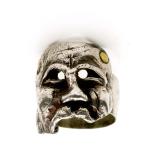 Photograph of a silver ring shaped like a tragic face.