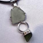 Photograph of a sea glass pendant on a black cord.